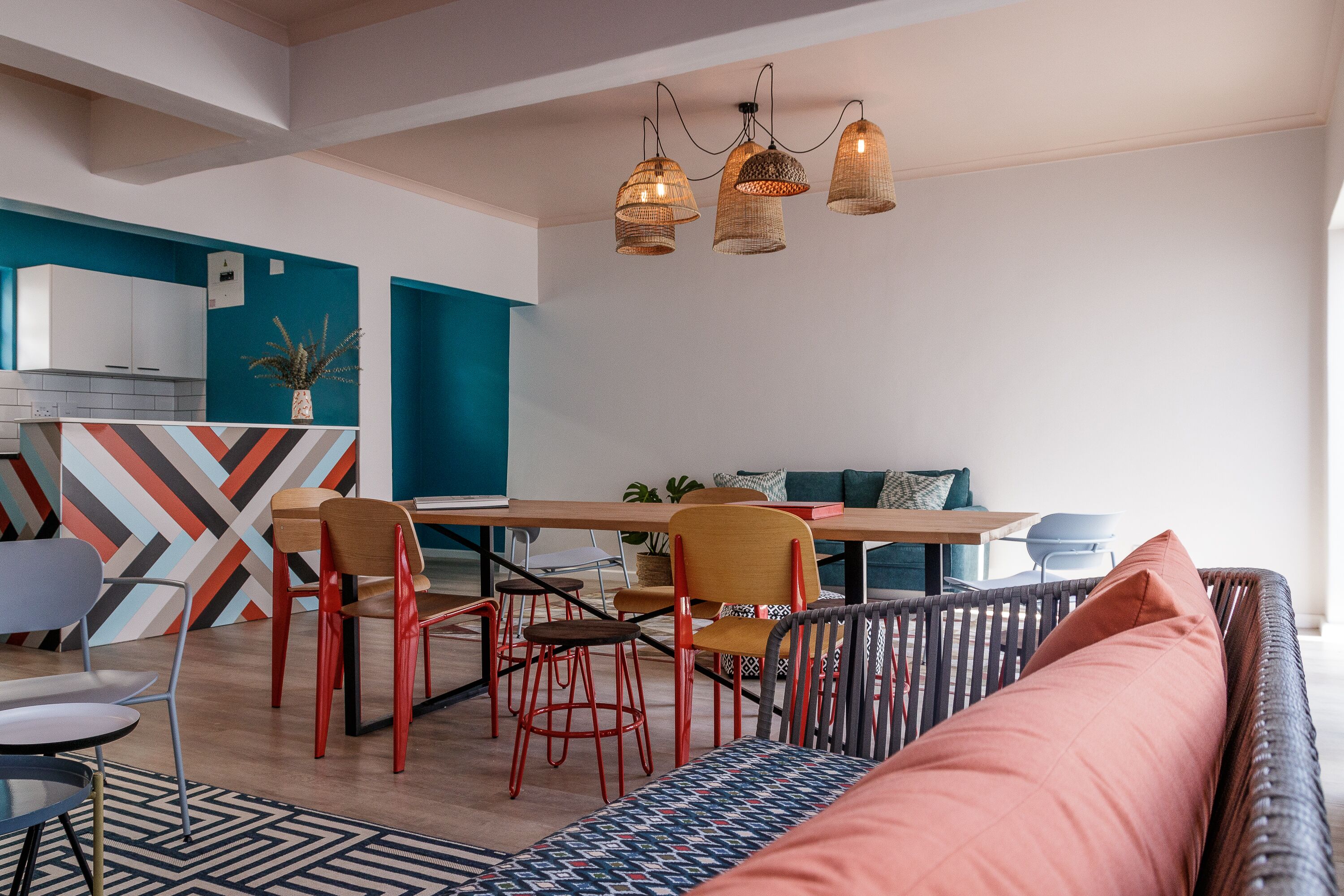Una cocina moderna con comedor, que presenta una mesa de madera, sillas rojas y una pared azul de acento.