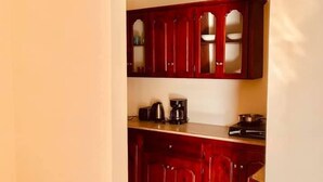 A kitchen with red cabinets, a countertop, and a coffee maker. - Solet's Paradise Negril (Negril)