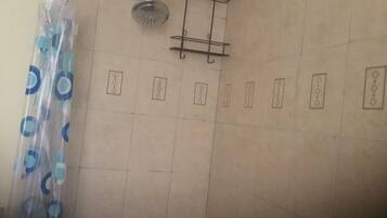 A tiled shower area with a showerhead and a metal rack.