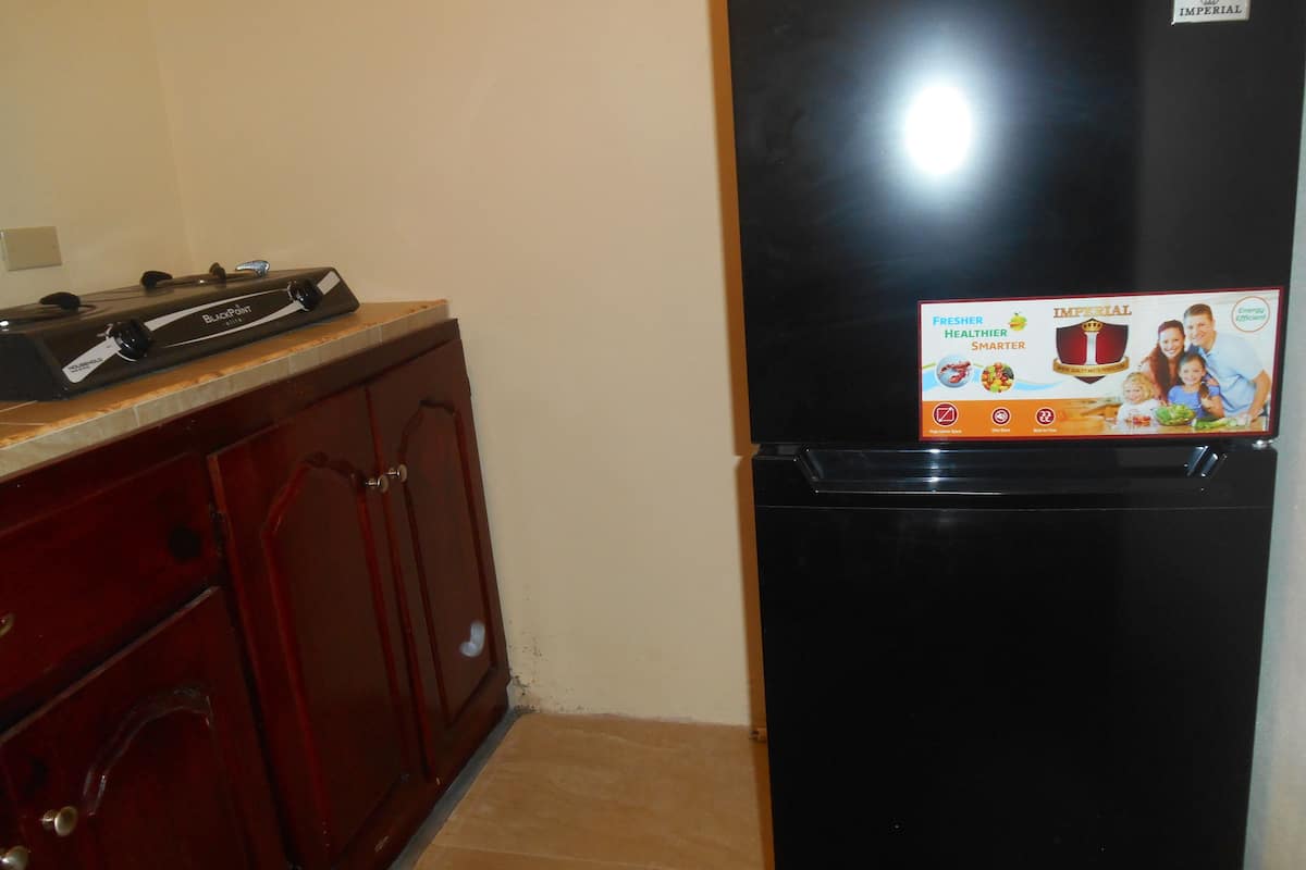 A black refrigerator with a fresh healthier smarter sticker, a wooden cabinet, and a tiled floor.