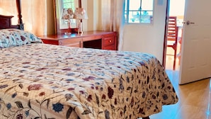 A bedroom with a large bed, a dresser, a mirror, and a door leading to an outdoor area. - Solet's Paradise Negril (Negril)