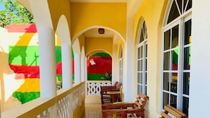 A covered corridor with wooden benches and tables, white railings, and large windows. - Solet's Paradise Negril (Negril)