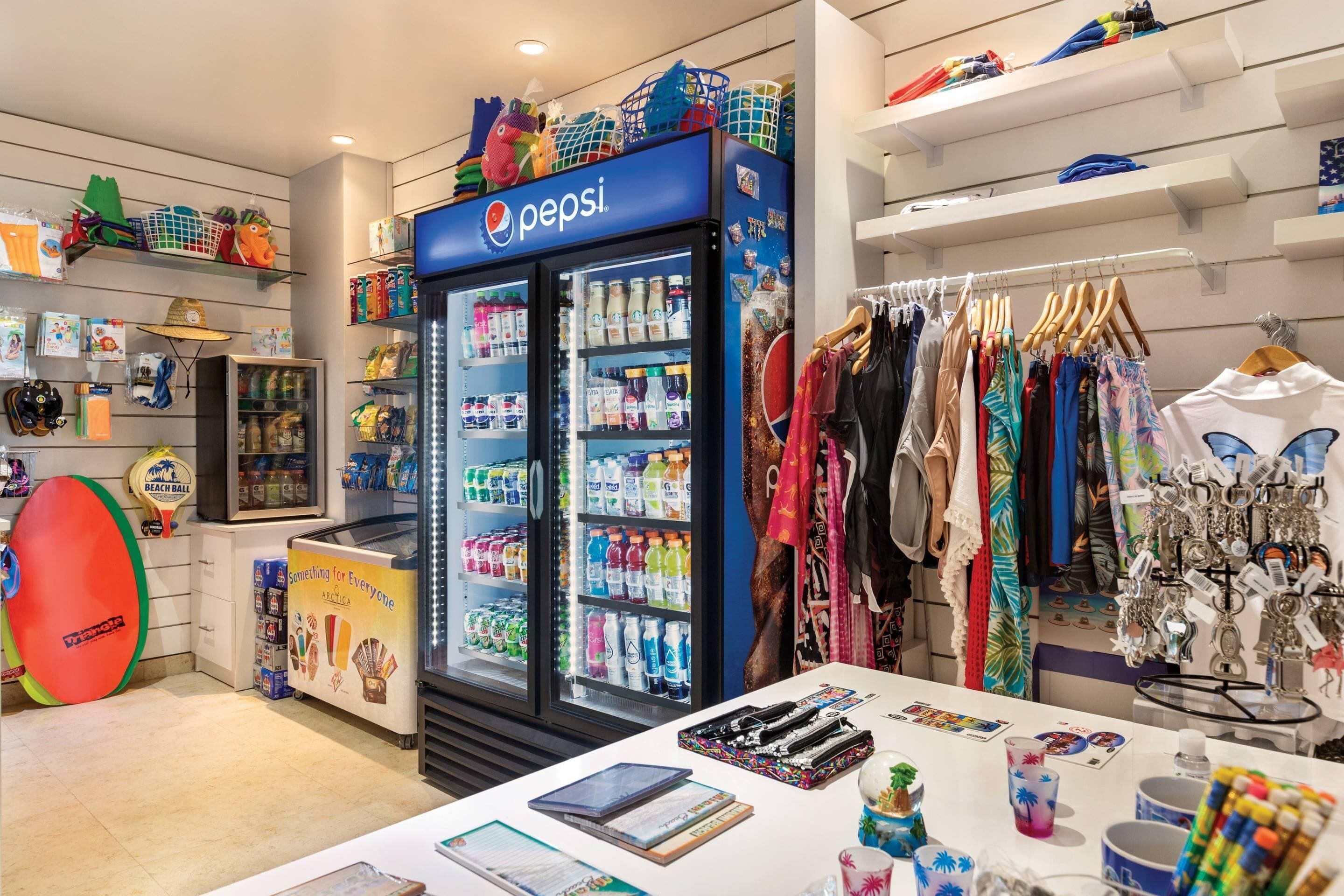 Una tienda con un refrigerador de Pepsi, perchas de ropa y diversos recuerdos.