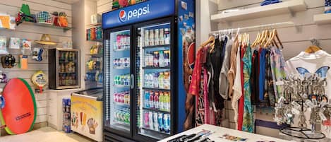 Una tienda con un refrigerador de Pepsi, perchas de ropa y diversos recuerdos.