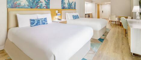 A hotel room with two beds, a desk, a chair, and a bathroom.