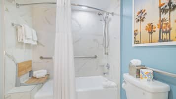 A bathroom with a shower, toilet, and a wooden shelf with towels.
