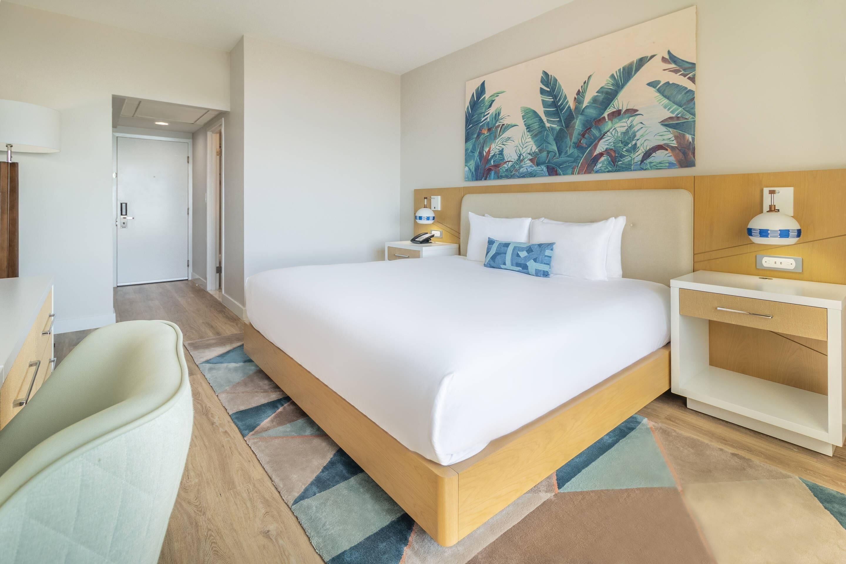 Una habitación de hotel con una cama grande, mesitas de noche, un escritorio y una silla.