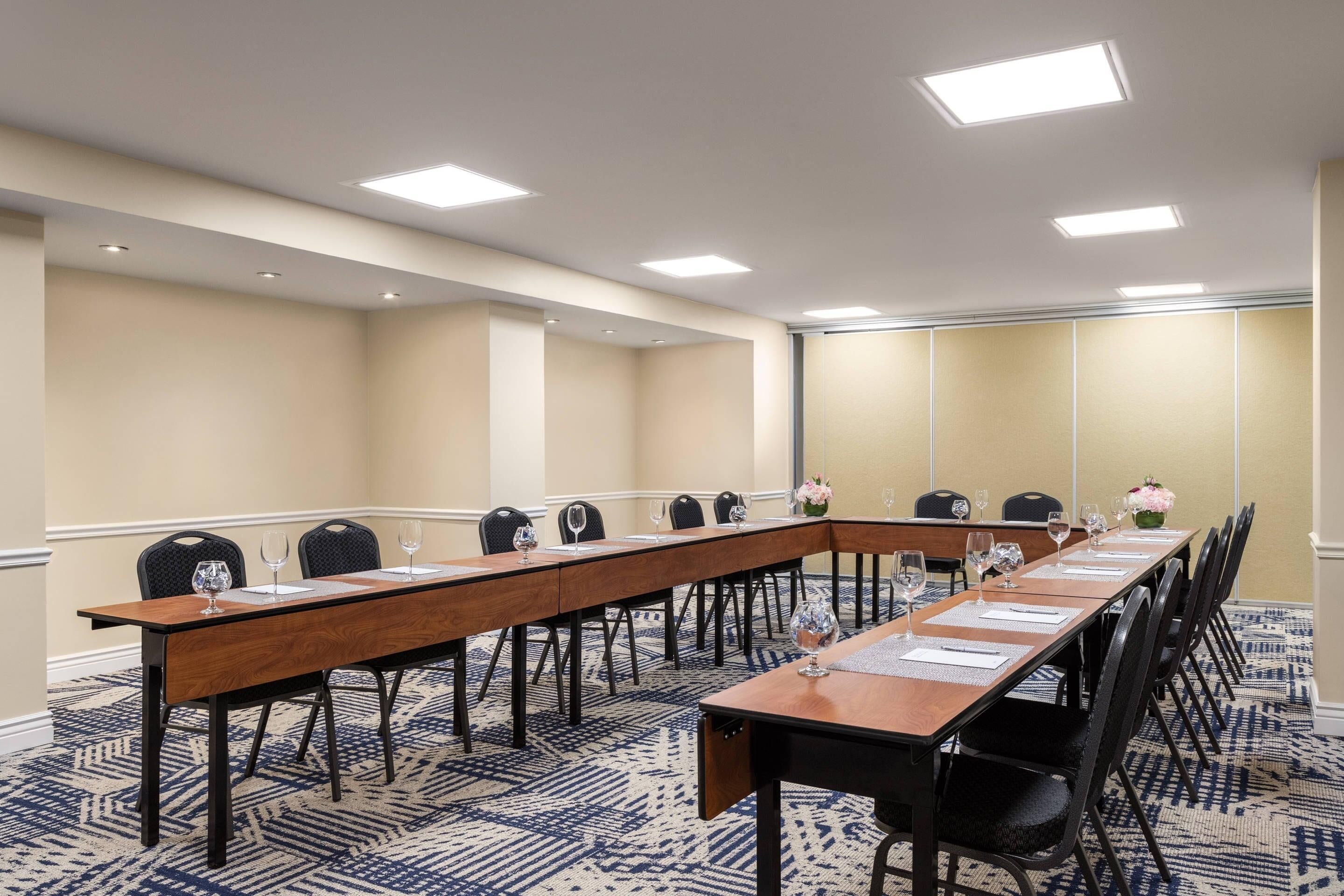 A conference room with a long table, chairs, and a carpeted floor.