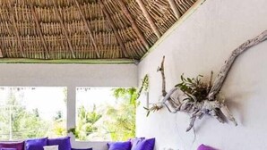 A modern living room with a large L-shaped sofa, round wooden coffee tables, and a decorative piece on the wall. - Casa Del Viento (Isla Holbox)