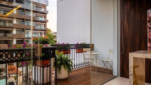 Ein Balkon mit Holzboden, einem weißen Tisch, einem weißen Stuhl und Topfpflanzen.