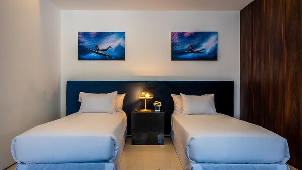Ein Hotelzimmer mit zwei Betten, einem Nachttisch mit Lampe und zwei Bildern an der Wand.