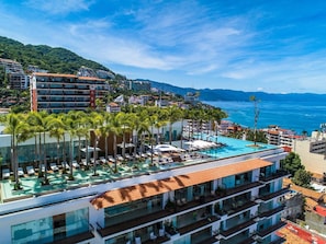A hotel with a rooftop pool, multiple balconies, and a view of the sea.