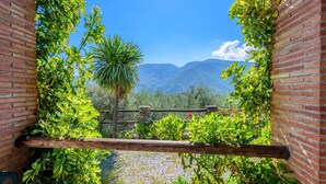 A view through a brick archway with lush greenery and a mountain backdrop. - Las Gallinas Órgiva by Ruralidays (Granada)