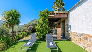 A patio with two sun loungers, a stone wall, and a covered area with a view of the countryside. - Las Gallinas Órgiva by Ruralidays (Granada)