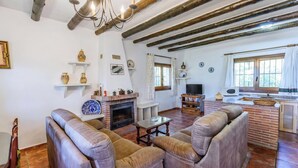 A living room with a fireplace, sofas, a television, and a kitchen area. - Las Gallinas Órgiva by Ruralidays (Granada)