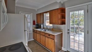 Una cocina con armarios de madera, un refrigerador, un fregadero y un ventanal con vista a una terraza.
