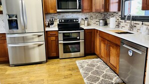 Una cocina moderna con electrodomésticos de acero inoxidable, armarios de madera y salpicadero de azulejos.