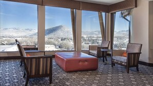 A hotel room with large windows offering a mountain view.