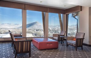 A hotel room with large windows, a red ottoman, and two armchairs. - Park City 1BR Prime Ski In/Ski Out Across from Waldorf  Heated pool/Hot tub (Park City)