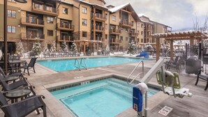 A pool area with two pools, lounge chairs, and a covered seating area.