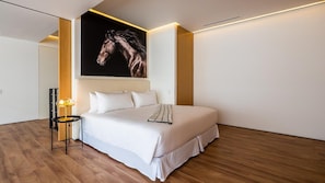 Ein modernes Schlafzimmer mit einem großen Bett, einem Nachttisch mit einer Lampe und einem an der Wand hängenden Kunstwerk.