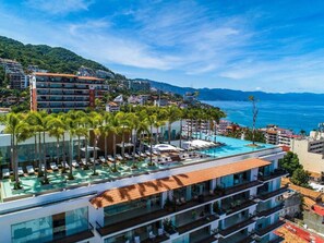 Et resort med swimmingpool på taget, palmer og havudsigt.
