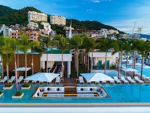 Zona de piscina en un resort con tumbonas, sombrillas y vistas de los edificios circundantes.