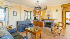 A living room with a sofa, a wooden coffee table, and a fireplace. - Villa el Pedregal Frigiliana by Ruralidays (Málaga)