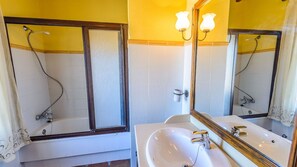 A bathroom with a bathtub, a sink, and a mirror. - Mansion Piedras Blancas Colmenar by Ruralidays (Málaga)