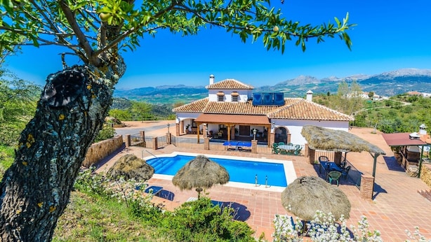 A villa with a swimming pool, outdoor seating, and a view of the surrounding landscape. - Mansion Piedras Blancas Colmenar by Ruralidays (Málaga)