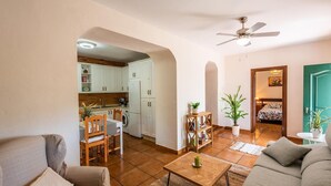 A spacious living area with a dining table, sofa, and kitchen in the background. - Casa Jazmín Azul Cómpeta by Ruralidays (Málaga)