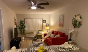 A living room with a red sofa, a coffee table, a TV, and a ceiling fan. - Hollywood Spacious Place (Los Angeles)