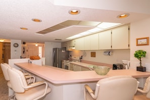 A kitchen with a central island, white cabinets, and recessed lighting.