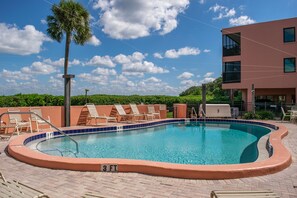 Relax by the pool surrounded by a brick patio and lounge chairs.