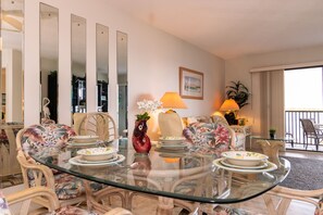 Enjoy meals in this stylish dining area with a glass-top table, wicker chairs, and a beautiful floral arrangement.