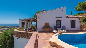 Una villa con piscina, mobiliario exterior y vistas al mar.