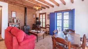 Una sala de estar acogedora con un sofá rojo, una mesa de comedor de madera y una puerta azul.