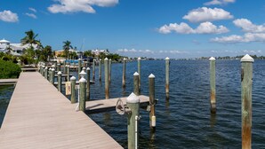 A wooden pier extending into calm water, with a clear sky and distant buildings.