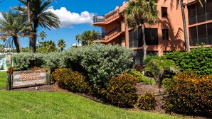A hotel with a sign reading "Cojina Mornings" surrounded by lush greenery and palm trees.