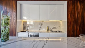 A modern kitchen with white cabinets, a marble backsplash, and a built-in dishwasher. - PIER 57 - 208 | 2BR Condo with Best Rooftop View (Puerto Vallarta)