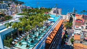 A rooftop pool with palm trees, a view of the sea, and a cityscape. - PIER 57 - 208 | 2BR Condo with Best Rooftop View (Puerto Vallarta)