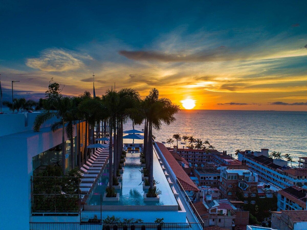 A resort with a pool, palm trees, and a sunset view.