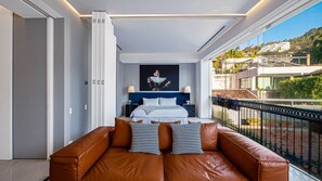 Un dormitorio moderno con una cama grande, un sofá y un balcón con vistas.