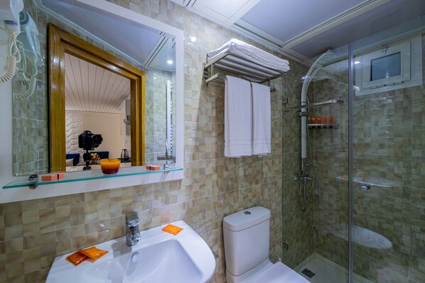 Un baño con cabina de ducha de vidrio, un lavabo blanco y un espejo sobre el lavabo.