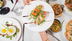 Una mesa de comedor con varios platos, incluyendo un plato con mariscos, un bol de ensalada y un plato con un huevo frito.