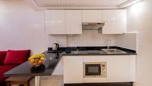 Una cocina moderna con armarios blancos, encimera negra y horno empotrado.