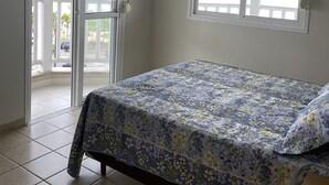 Een slaapkamer met een bed, een raam en een deur naar een balkon.