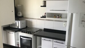 Een kleine keuken met een fornuis, oven, magnetron en koelkast.
