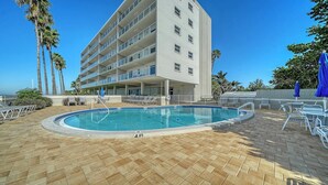 Ett hotell med en pool, palmer och en klarblå himmel.