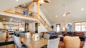 A spacious living area with a dining table, a sofa set, and a staircase leading to an upper level. - Group Ski Getaway Near the Base of Chairlift 8! (Brian Head)